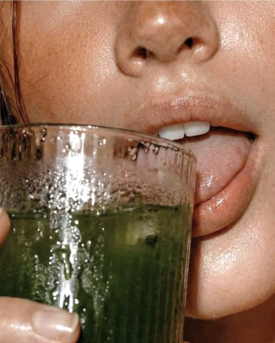 Primer plano de una persona bebiendo un vaso de bebida verde